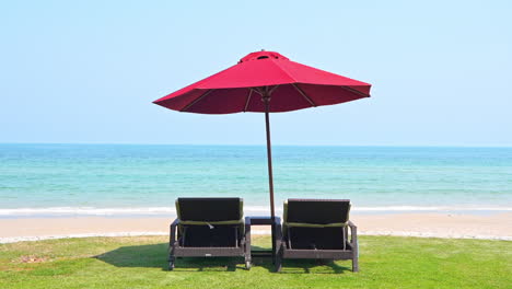 empty beach, two beach beds and umbrella in front of tropical sea and horizon