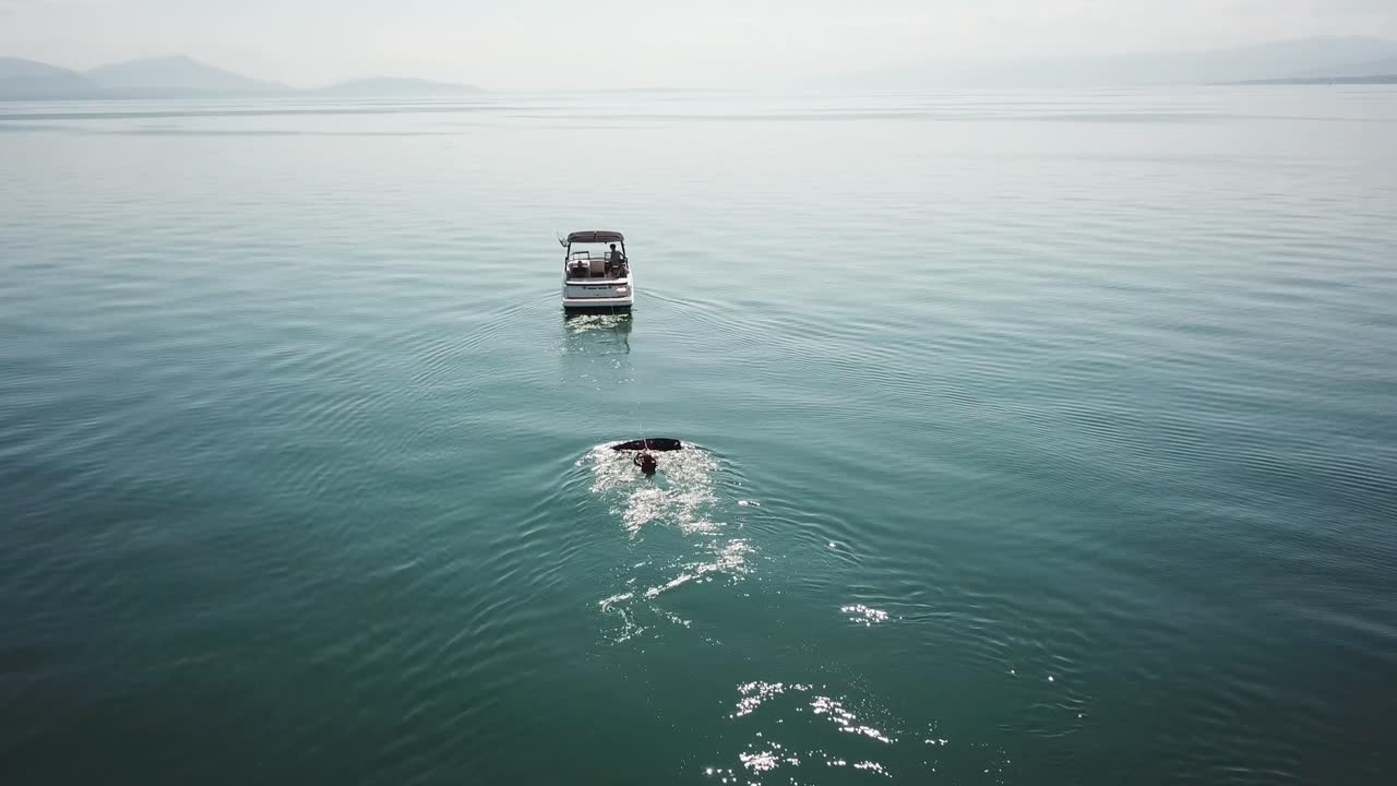 웨이크보더는 물에서 시작할 준비가 되어 있으며 보트가 가속되기를 기다리고 있습니다. 공중 드론 보기, 스위스