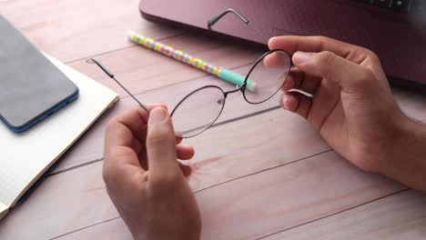 person adjusting glasses at a desk