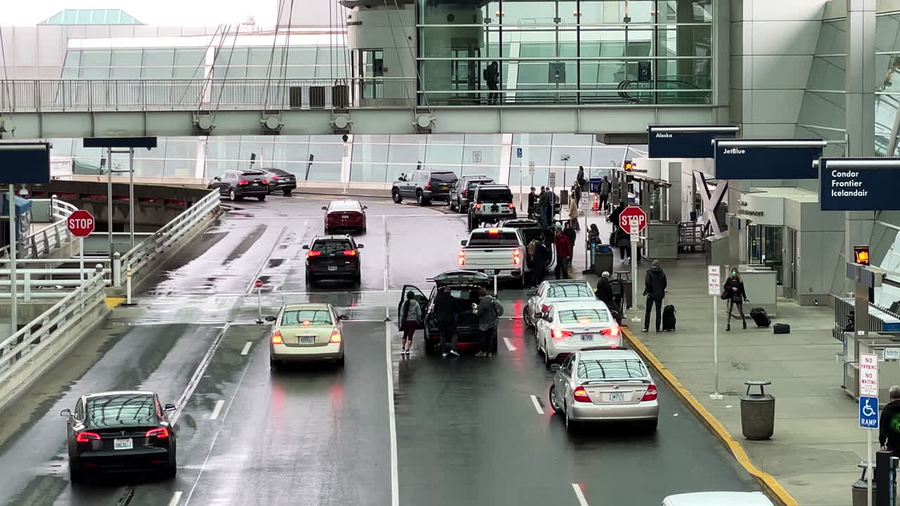 Travelers putting luggage into vehicles after arriving into Portland International Airport, handheld view