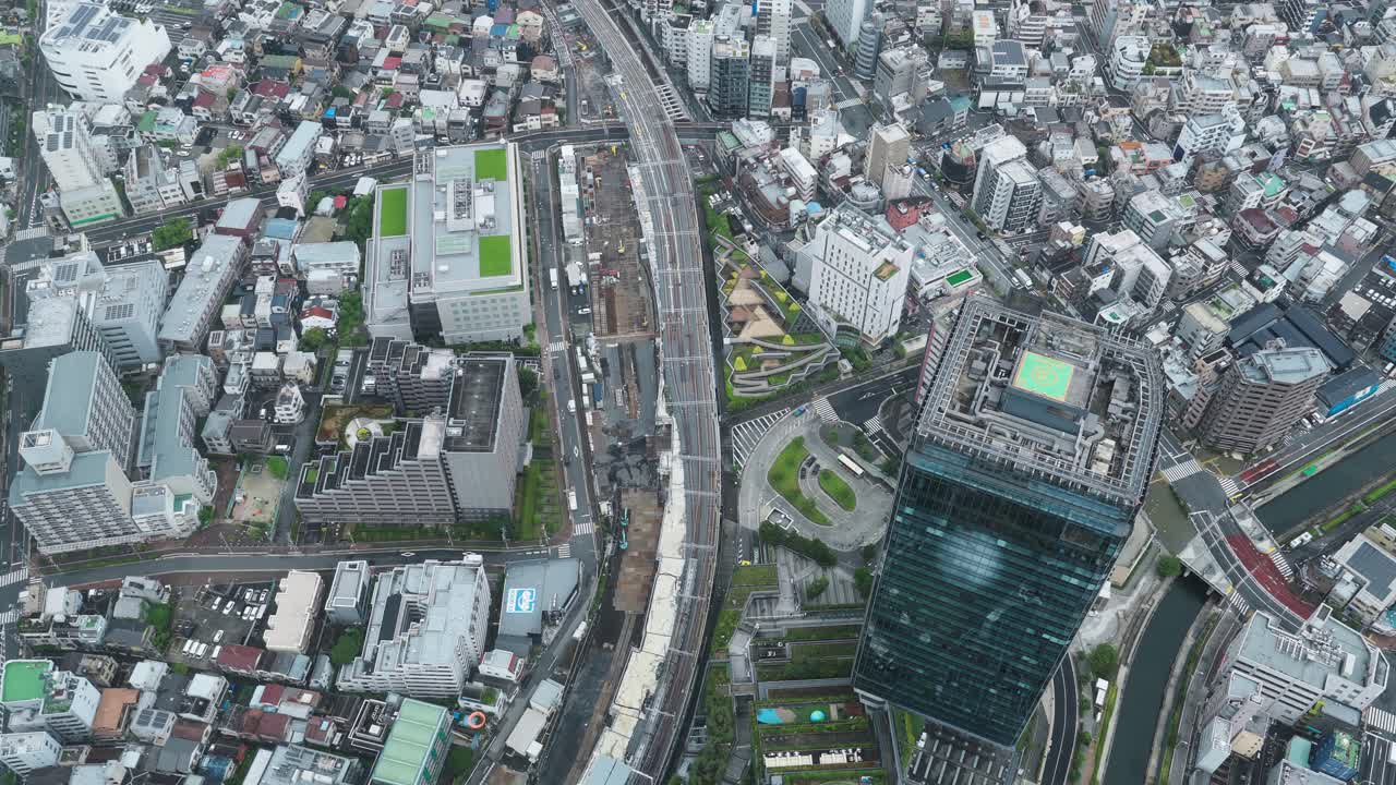 A high-angle, wide shot of a dense, bustling urban landscape in Tokyo, showing a mix of modern and older buildings