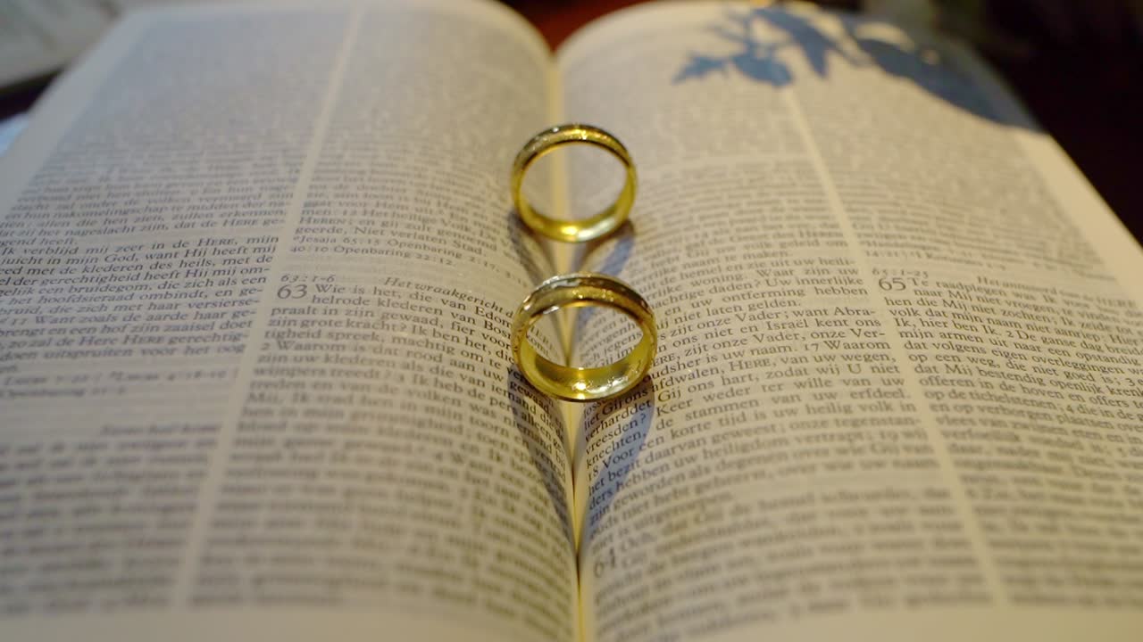 Wedding rings forming heart shadow in bible, close up