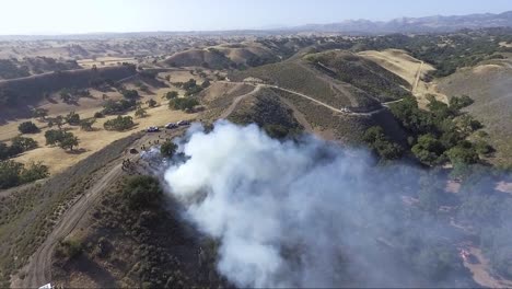 aerial - firefighters stop a fire from the top of the hill