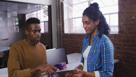 Diverse-female-and-male-business-colleagues-in-discussion-at-work-looking-at-digital-tablet