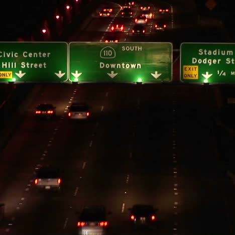 A-time-lapse-of-vehicles-driving-on-the-freeway-and-under-signs-at-night