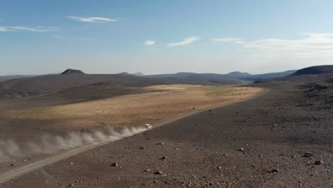 Toma-Aérea-Siguiendo-A-Un-Automóvil-Que-Levanta-Una-Gran-Nube-De-Polvo-Mientras-Acelera-A-Lo-Largo-De-Un-Polvoriento-Camino-Del-Desierto.-Vehículo-Con-Vista-De-Drones-Acelerando-En-Una-Carretera-De-Polvo-En-Islandia-Explorando-Un-Paisaje-Increíble