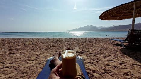 sentado en una playa del mar rojo disfrutando de un cóctel