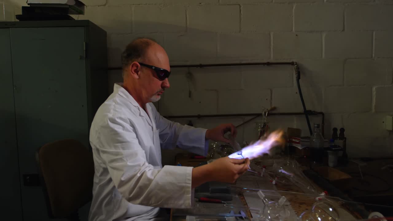 vista lateral de un trabajador masculino maduro haciendo vidrio en una fábrica de vidrio 4k