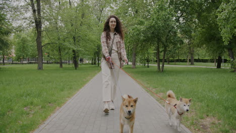 woman walking two dogs in a park