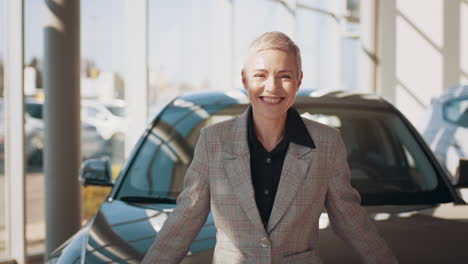 mujer sonriendo frente a un coche en un concesionario