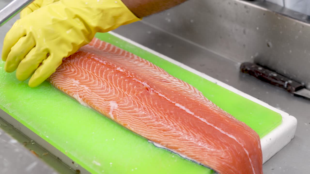 A skilled chef passionately works with a vibrant salmon fillet, showcasing precision and technique in a lively kitchen setting as dawn breaks outside