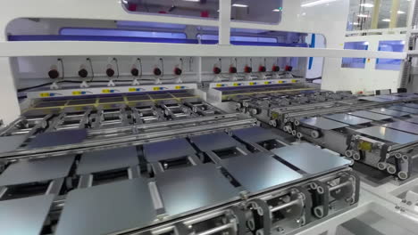 Automated-solar-panels-being-moved-by-robot-arms-on-conveyor-belts-during-high-tech-production-process-in-renewable-energy-factory,-Photovoltaic-cells-being-placed-on-assembly-lines