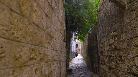 small traditional narrow alley in old historic town in europe with stone walls and cobblestones