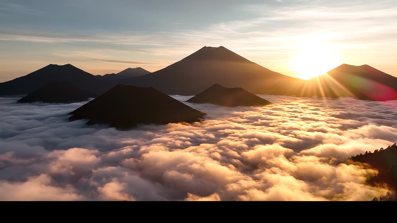 Lever de soleil sur des pics volcaniques émergeant d'une mer de nuages