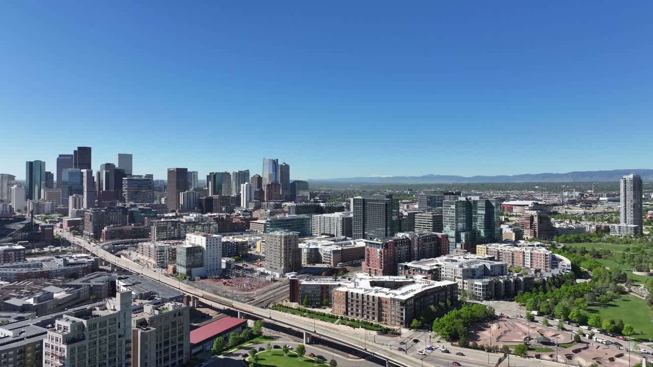 Aerial view of downtown Denver as the drone flies sideways with a clear blue sky above the city