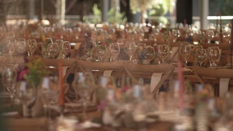 long tables with floral decor and glassware arranged for wedding reception under warm light