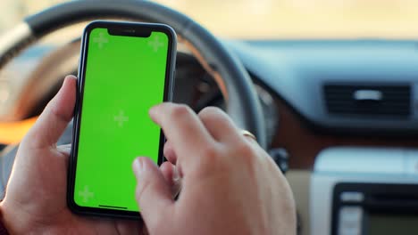 hombre de mano usando teléfono móvil chromakey con pantalla verde vacía en un coche moderno. maqueta de pantalla táctil. búsqueda en internet.