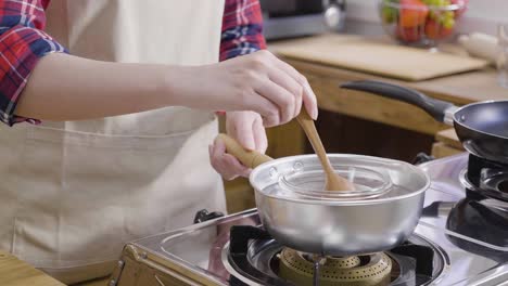 mujer derritiendo chocolate oscuro a mano en una olla caliente