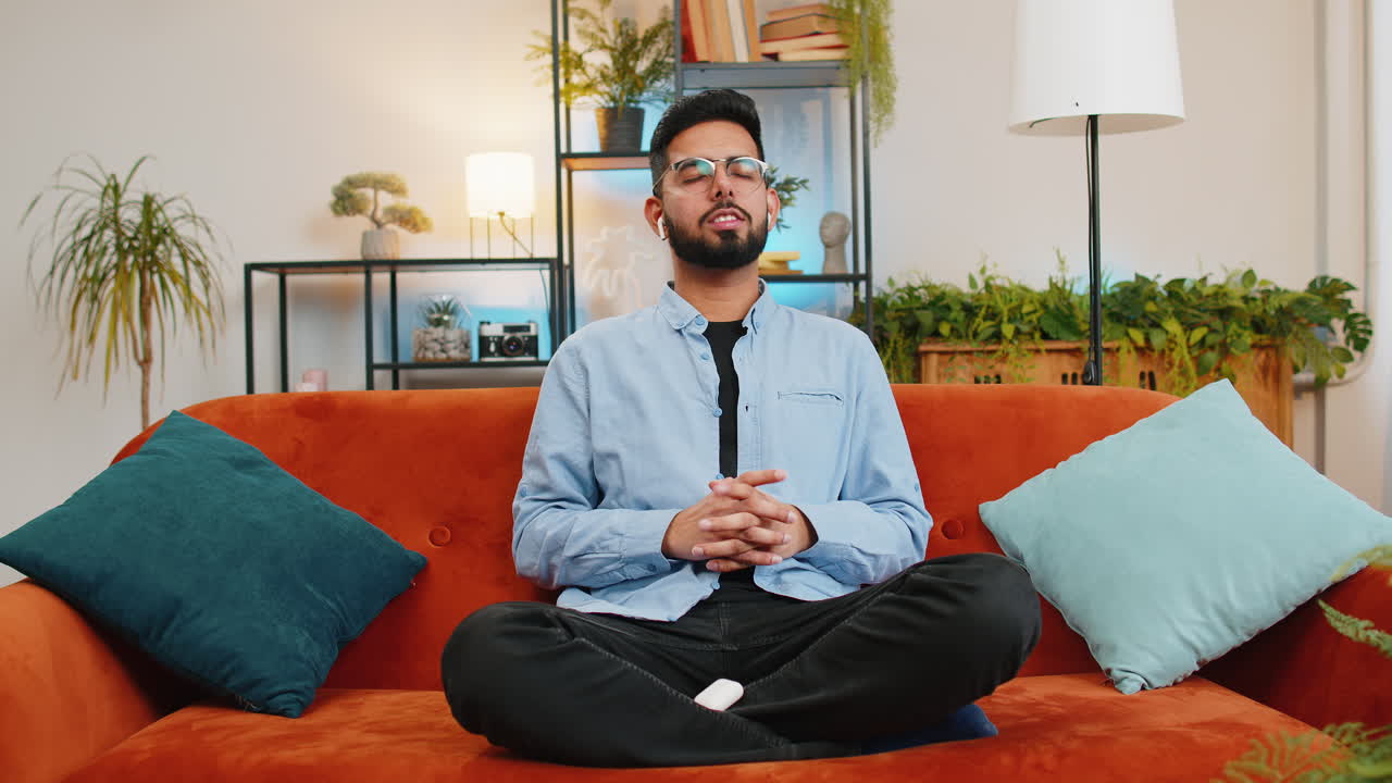 Indian man taking wireless earphones out of box placing gadgets in ears starting listening to music