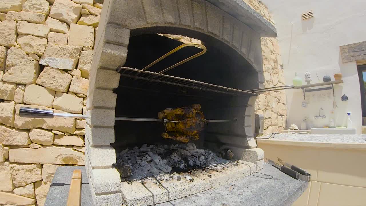 Odun ve kömür ateşinde, tuğla mangalda yavaş çekimde (200fps'den 50fps'ye düşürülmüş) dönen çevirme tavuk ızgara oluyor