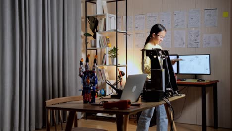 teen asian girl looking at the picture in hand, thinking, and walking around while working about a cyborg hand at home