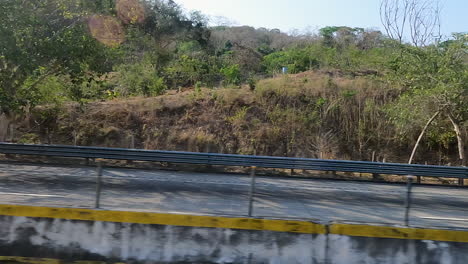 A-drive-along-a-highway-with-lush-green-mountains-and-foliage-on-either-side