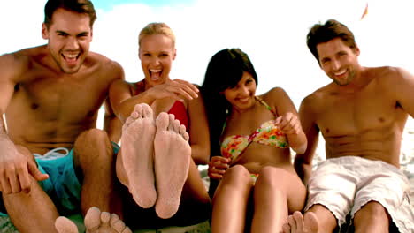 Friends-sitting-up-together-on-the-beach-and-smiling