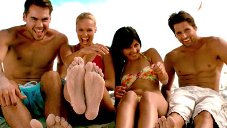 amigos sentados juntos en la playa y sonriendo