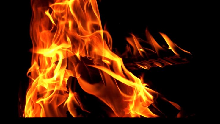 Carboni ardenti nel fuoco. Fiamme su sfondo nero. Rallentatore.