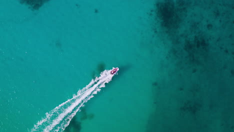 una vista aérea de arriba hacia abajo de una lancha a motor que atraviesa el mar