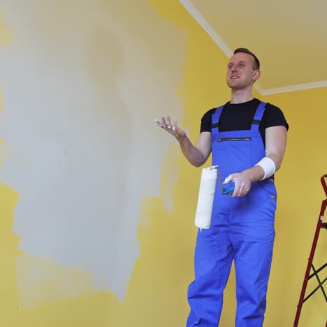 man painting walls with roller. workman in the uniform painting the walls with paint roller