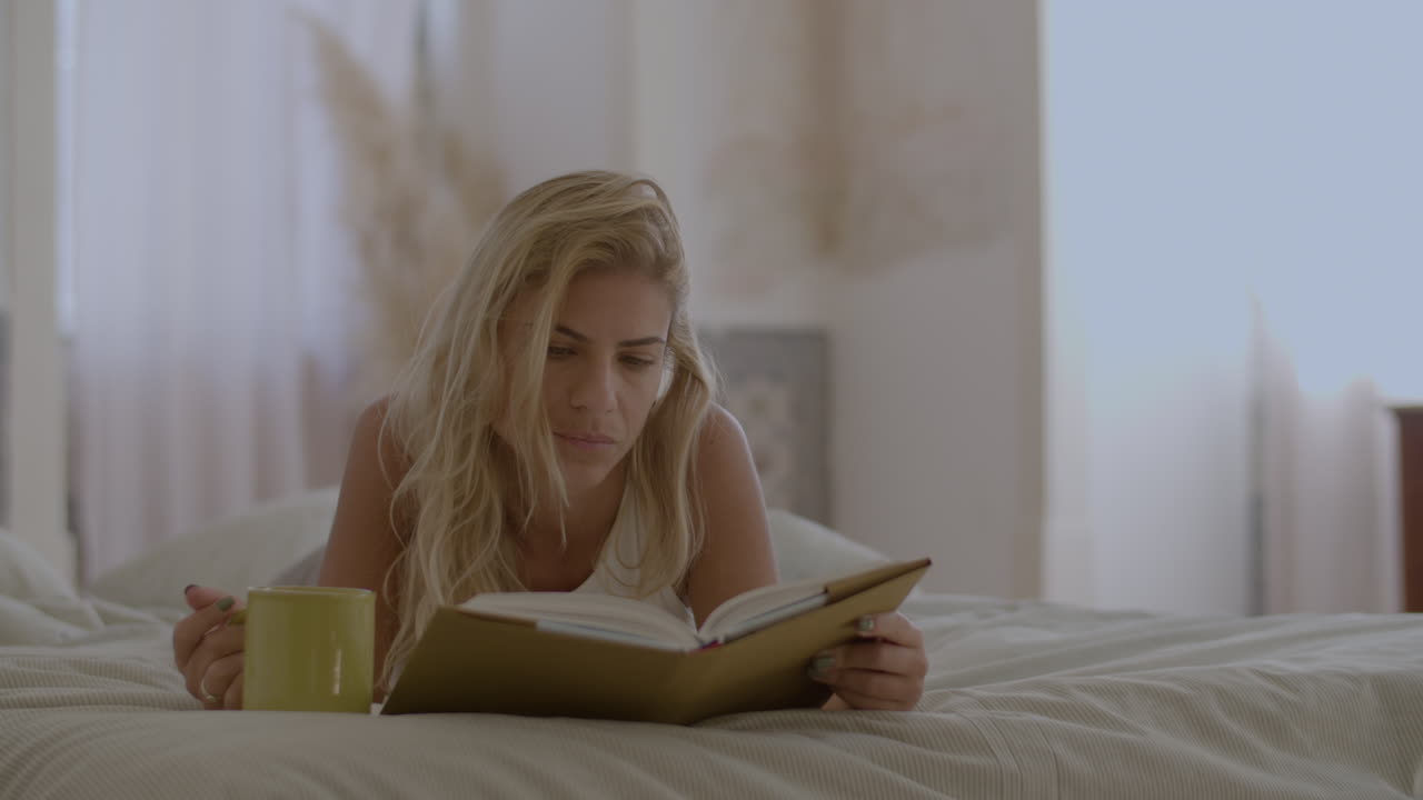 침대에 누워서 아침에 책을 읽는 집중된 여성