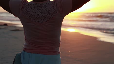 Senior-woman-standing-with-arms-outstretched-on-beach-