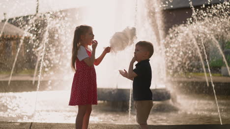 Little-kids-put-spun-sugar-pieces-into-mouths-near-fountain