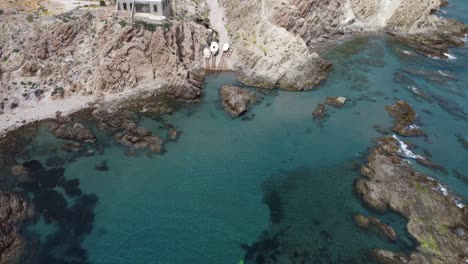 flying-away-from-a-beach-with-boats-surounded-by-cliffs-while-panning-up