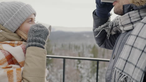 couple enjoying hot drinks on a snowy mountaintop