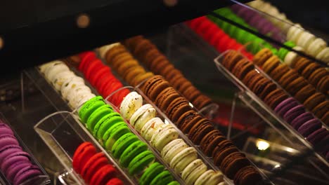 ver en una vitrina de cristal de coloridos macarons en una panadería de gama alta con poca luz