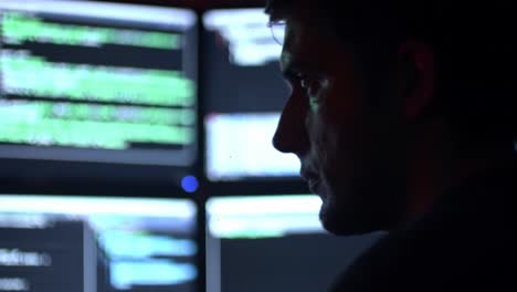 a focused cybersecurity professional analyzing complex data on multiple monitors in a darkened environment to safeguard digital systems