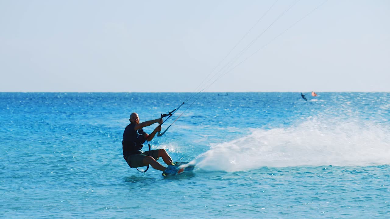 Slow motion shot of male kite surfer lifting off the beautiful blue ocean in Bonaire, Caribbean