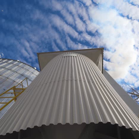 metal construction on the modern factory. storage tanks for processing grains on sky background. smoke releasing from industry into the air. close-up. motion camera top down
