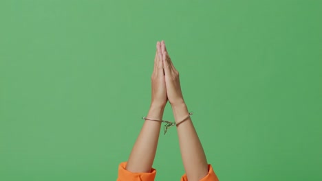 cerca de las manos del prisionero masculino en esposas que se levantan haciendo un gesto de la mano de oración pidiendo algo en el fondo de la pantalla verde