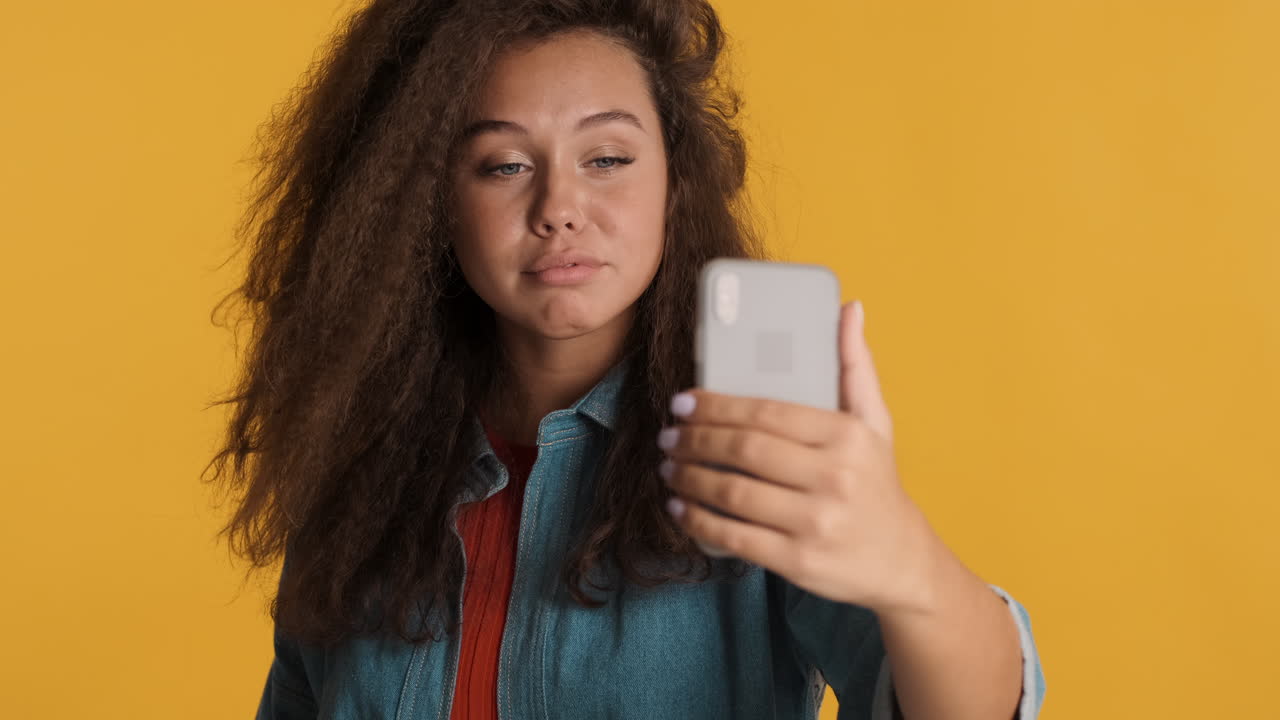 Caucasian curly haired woman video calling on smartphone.