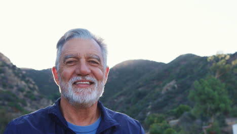 Portrait-Of-Smiling-Hispanic-Senior-Man-Outdoors-In-Countryside-Against-Flaring-Sun