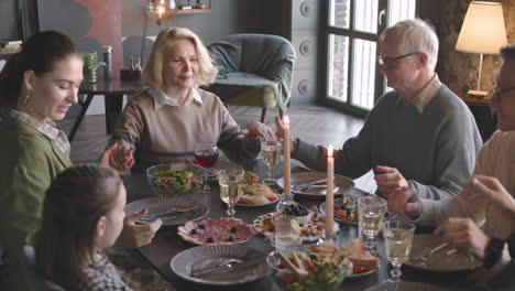 senior woman sitting at dinner table and praying before meal with her family at home 2