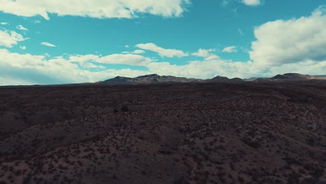 Desert-hills-with-mountain-in-background-flying-in