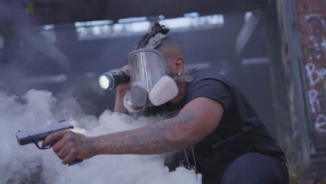 a masked man with a pistol and flashlight takes aim through heavy smoke in a gritty, graffiti-covered industrial setting. tense and dramatic visual