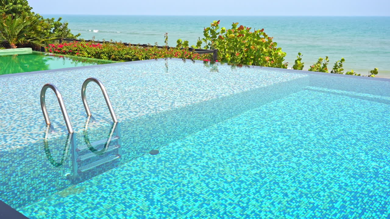 An empty resort swimming pool overlooks the ocean horizon
