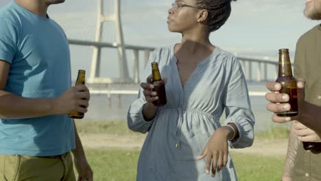 cheerful friends clinking beer bottles and dancing