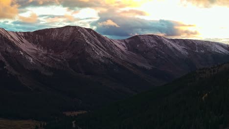 drone view soaring over a winding road through green valleys and snow-capped mountains in independence pass