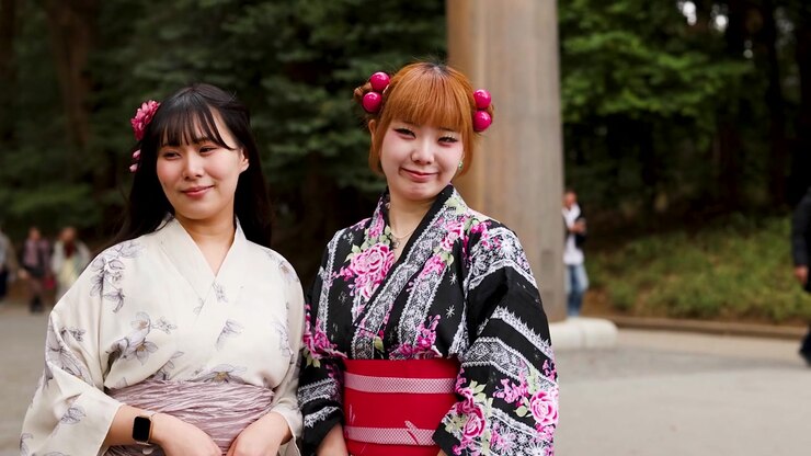 Due giovani donne che indossano yukata tradizionali e ornamenti per capelli sorridono al Santuario Meiji, Tokyo.